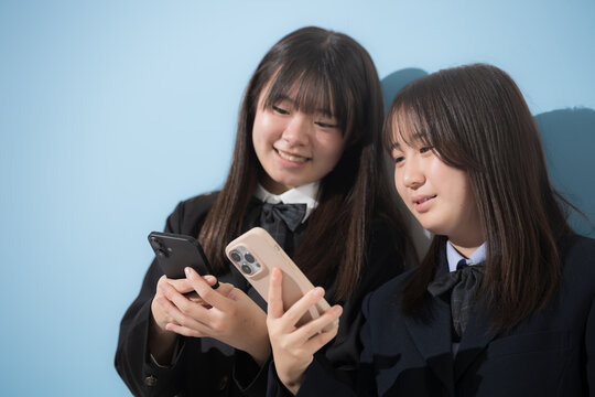 スマートフォン(スマホ)を見る日本人女子中学生、女子高校生　2人で情報を共有する学校生活とコミュニケーション、スマホの安全な使い方イメージ