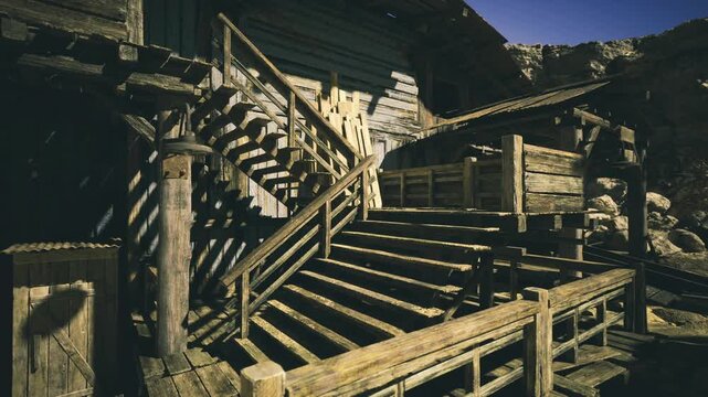 Sunlit wooden staircase leading into shadowed loft area, steep steps and carved railing show aged craftsmanship, dramatic diagonal lines and strong contrast