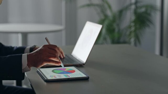 ノートパソコンとタブレットPCを使って作業する男性ビジネスパーソン。オフィス、ビジネス、デスクワーク