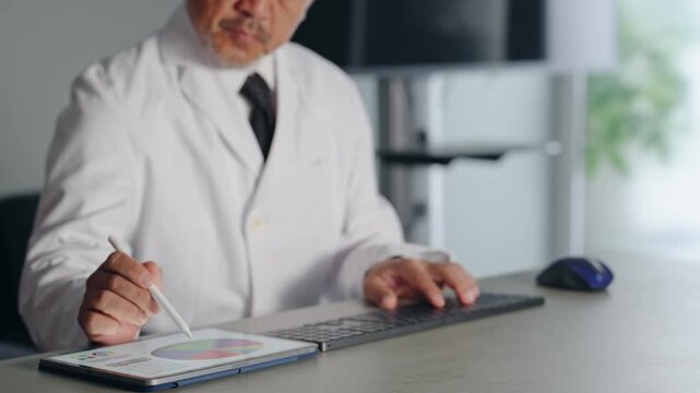 A man in a white coat working with a computer and a tablet PC. Doctor, scientist, researcher, DX, IT, engineer, work.