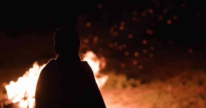 A young Masaai boy watching a traditional fire dance at night in Kenya.