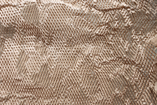 Eco-friendly honeycomb paper wrap, sustainable packaging material for protective shipping, abstract brown kraft paper texture background.