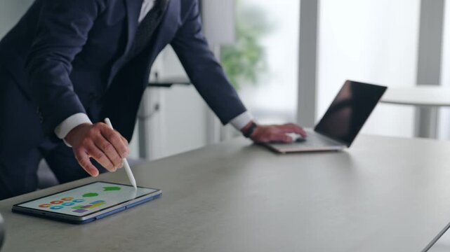 A man working with a laptop and a tablet PC. Business, DX, AI, IT, work, office, operation.