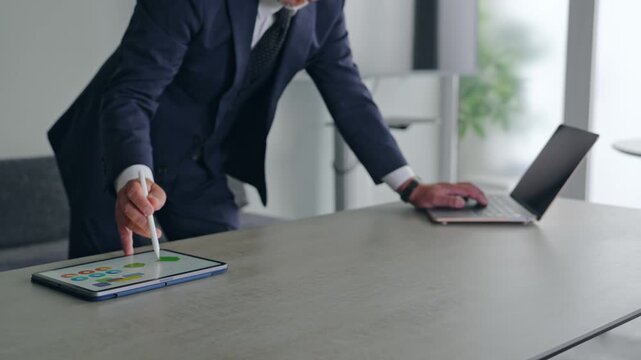 ノートパソコンとタブレットPCを使って作業する男性。ビジネス、DX、AI、IT、仕事、オフィス、操作