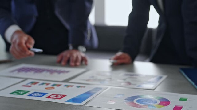Male and female business professionals reviewing documents during a meeting. Management, strategy, teamwork, business negotiations, planning, guidance, training, information.
