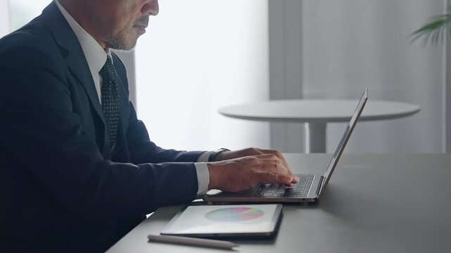 ノートパソコンとタブレットPCを使って作業する男性。DX、IT、ビジネス、オフィス、仕事、事務、業務