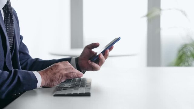 スマホとPCを使って作業する男性ビジネスパーソン。アプリ、SNS、ビジネス、クラウド、ERP、DX