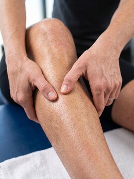 Physical therapist massaging the calf of a patient for pain relief