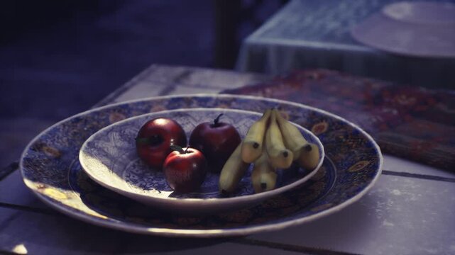 Vintage porcelain bowl filled with fruit, detailed blue gold rim with bananas and red apples, soft vignette and market table styling in Mutrah Souq evoking