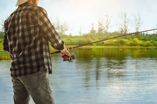 Back view of man fishing by river under blue sky