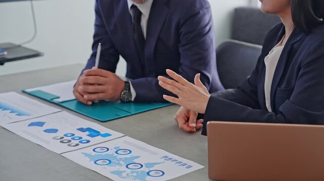A group of business professionals conversing while looking at documents. Meetings, strategy, management, teamwork, consultation, business negotiations, conversation.
