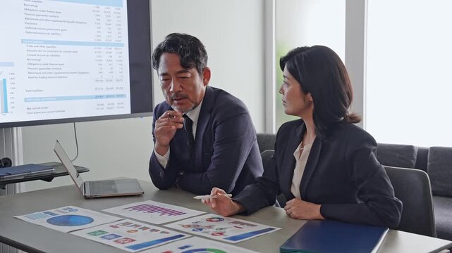 書類を見ながら会話するビジネスパーソンのグループ。チームワーク、経営、企業、人材、相談、戦略、同僚
