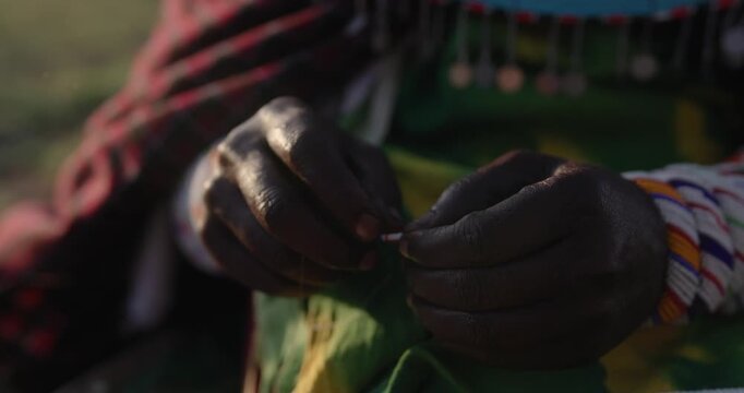 Hands of a Samburu woman crafting traditional beaded jewellery in Laikipia, Kenya.