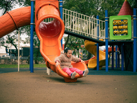 Child slides down an orange playground slide