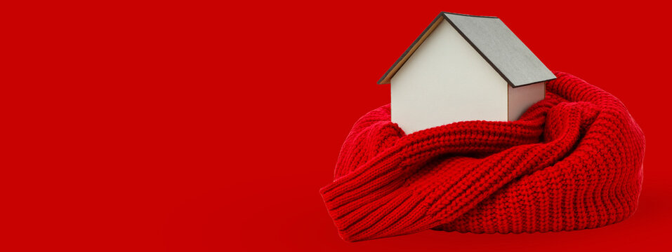 A house is snugly wrapped in a red knitted scarf for warmth