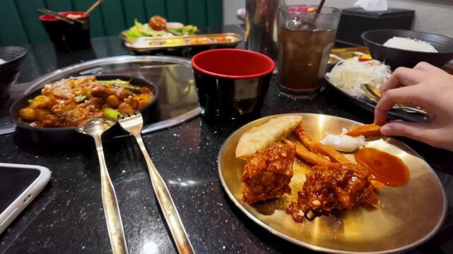 Person Dipping Sweet Potato Fry into Sauce at Asian Restaurant