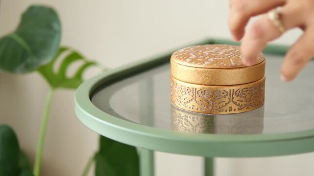 Gold round box on glass table with green plant