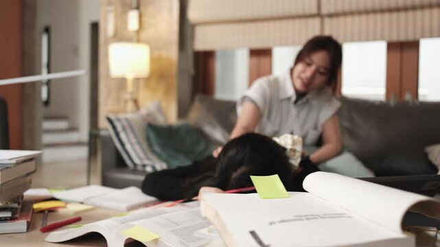 Two College Asian friends, teenage girl tired and burned out from overwhelmed homeschooling, study pile of books, stressed learning at home, her friend wakes up while napping, education exam support.