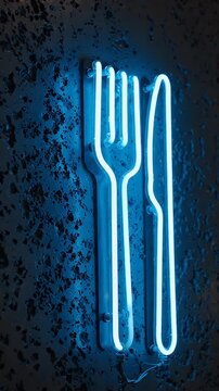 Neon Fork and Knife Sign on Textured Wall - A bright blue neon sign shaped like a fork and knife glows against a dark, textured, gray wall.