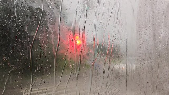Rainy window view with water droplets, moody atmosphere, blurred background scenery