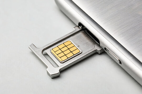 A SIM card tray with a golden chip is partially pulled out from a sleek metallic smartphone, showing internal hardware components.