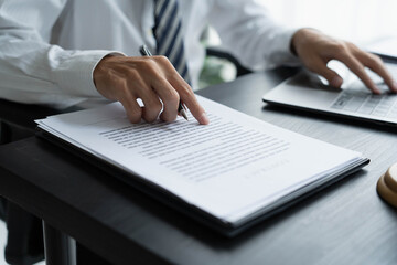 Fototapeta premium Lawyer checking documents and typing on laptop