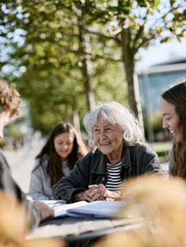 Senior woman smiles warmly with young students outdoors