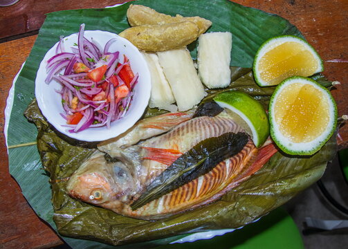 A grilled Amazonian dish, Maito de Tilapia, is fish wrapped in bijao leaves, cooked over charcoal or wood, and served with yucca, plantain (banana), salad, and lemon. Ecuador