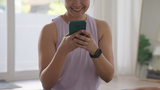 Young active Gen Z woman using smart watch phone wrist wear check app heart rate zone AI report after home workout Health care internet of things asia people happy cheerful anti aging life weight loss