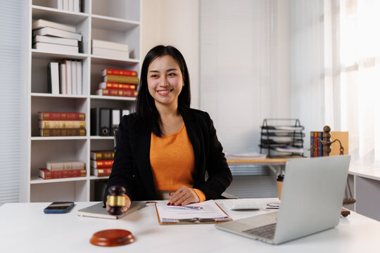 Smiling professional asian woman lawyer holding law gavel in office, justice and legal advisor working, representing client, handling dispute, and providing legal counsel expertise