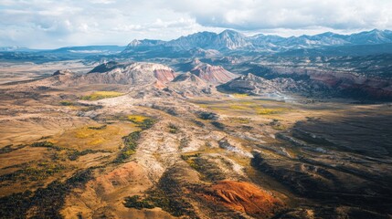 Aerial view of a vast, arid landscape with colorful rock formations and distant mountains © stock.finder