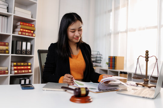 Young asian woman working intently in her law office, reviewing documents and legal papers, demonstrating dedication to her professional legal practice