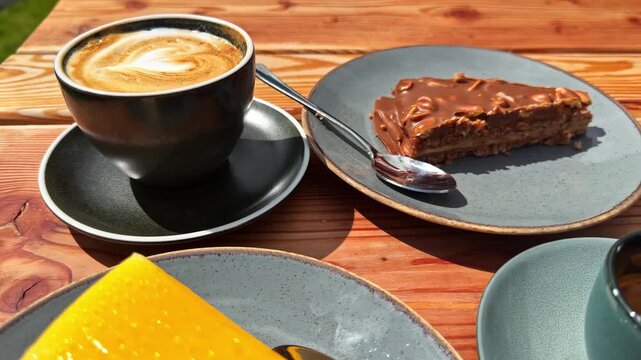 Cup of coffee with chocolate pie slice on plate, outdoor setting.