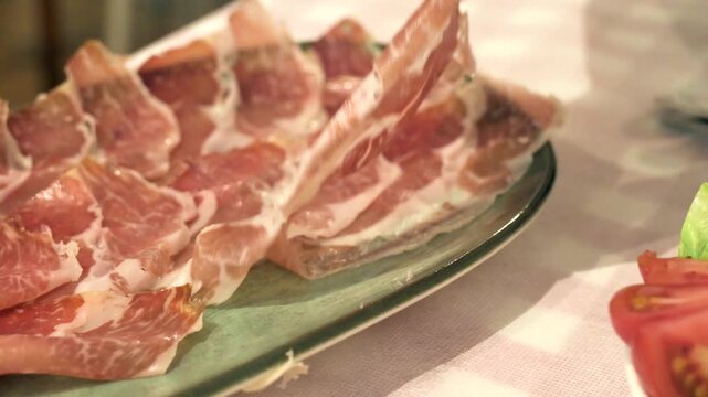 Person picking up a piece of authentic cured jamon from a traditional tapas platter