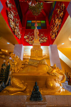 A magnificent golden chedi pagoda statue on the shell of a dragon turtle sculpture inside the colorful hall at Wat Thai Samakkhi temple in Mae Sot, Tak, Thailand.