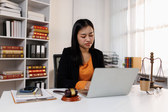 Professional asian lawyer working on litigation cases using a laptop in a modern law office representing justice, legal services, and online consultation for clients focusing on legal advice