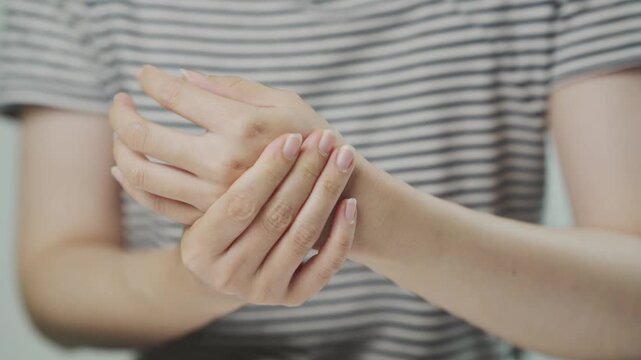 Woman holding her painful wrist, illustrating wrist pain, hand injury, repetitive strain, tendon inflammation, office syndrome, arthritis symptoms, healthcare, rehabilitation, and medical wellness con