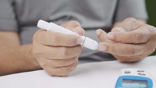 Close-up of a senior adult using a blood glucose lancet device for a fingertip diabetes test at home. Healthcare monitoring, blood sugar control, self care, chronic disease management and wellness.
