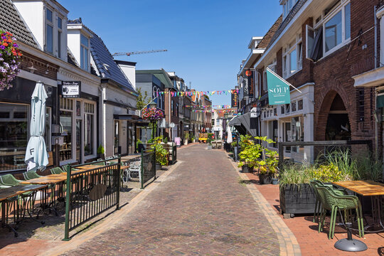 Bussum, Netherlands. 13 July 2026. A vibrant pedestrian street featuring outdoor cafe seating, brick paving, historic buildings, and festive flags overhead.