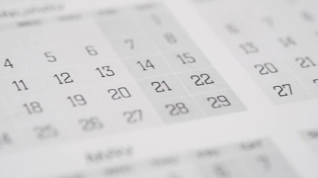 Close up camera panning across a desk calendar showing various months and dates in motion