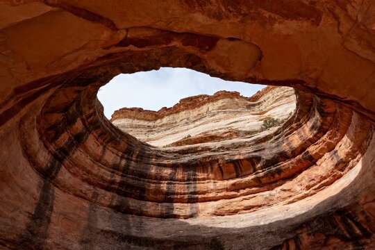 Natural rock arch formation with layered sandstone and sky view