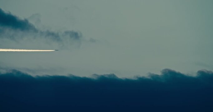 Aircraft contrail stretching across a dramatic cloud layer at dusk.
Minimal evening sky with a high altitude vapor trail and moody
atmospheric clouds.
