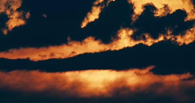 Close Up of dramatic storm clouds illuminated by golden sunset light. Moody cloud formations and atmospheric evening sky create a striking weather scene.