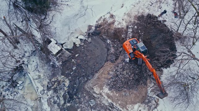 Overhead View Of Excavator Working On The Creek Covered In Fresh Snow In Winter. - aerial shot