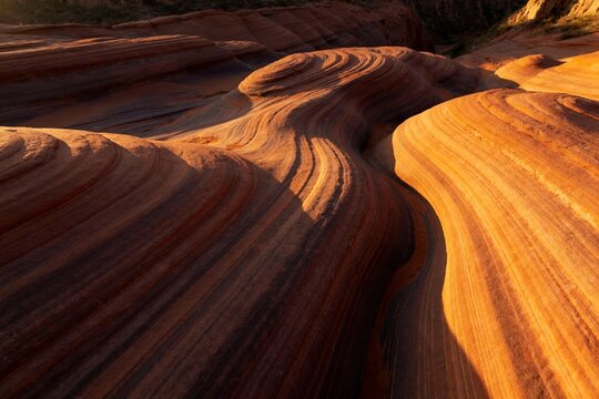 Wavy sandstone formations with layered textures illuminated by warm sunlight