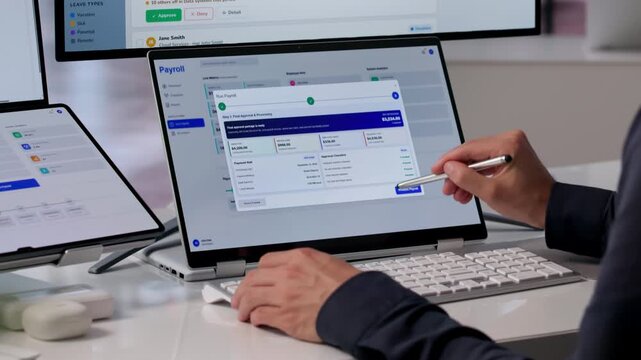 HR Manager Reviews Payroll Software On Dual-screen Laptop