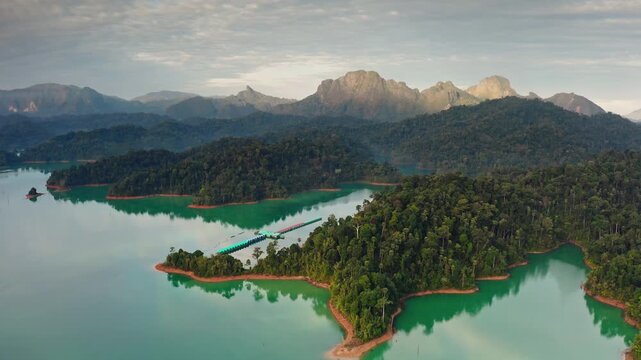 Amazing aerial landscape of Cheow Lan Lake overwater bungalow resort with turquoise waters and lush rainforest islands, surrounded by stunning limestone karsts of Khao Sok National Park in Thailand