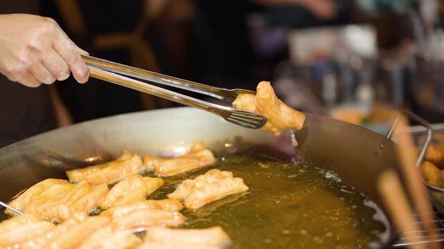 Chef Deep Frying Traditional Thai Dough Sticks in Large Wok