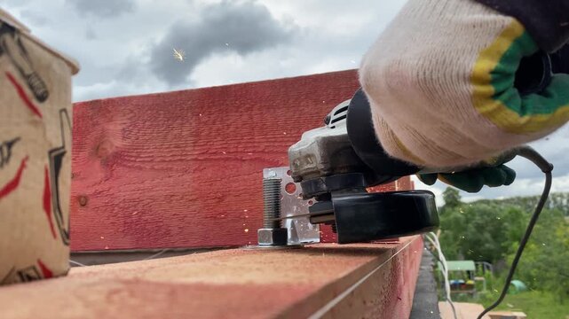 Worker Cutting Steel Bracket with Angle Grinder Outdoors