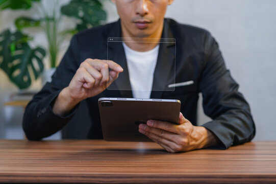 Businessman Interacting with Transparent Digital Interface While Using a Tablet at Office Desk
